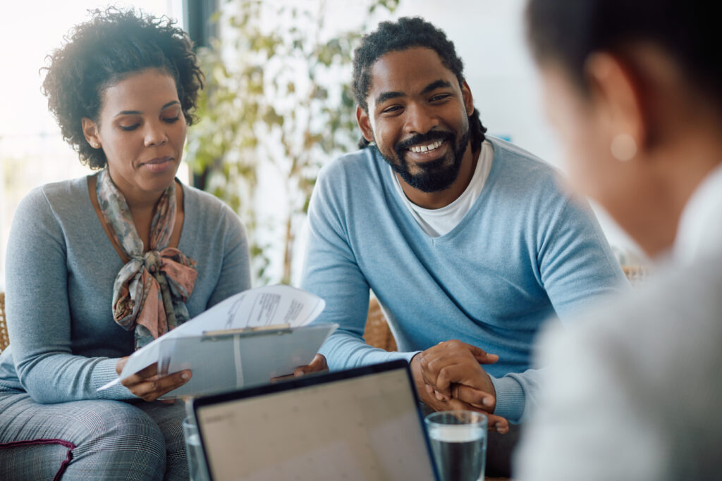 Happy black couple goes through paperwork with a financial advisor.